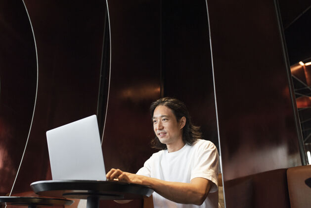 韩文男人在一个现代的办公空间里用笔记本电脑工作亚文中文科技