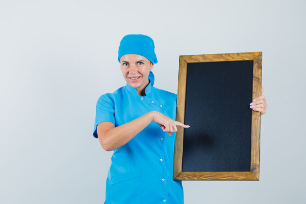 成人身着蓝色制服的女医生指着黑板 神色开朗 正对着前方看制服女人工作人员
