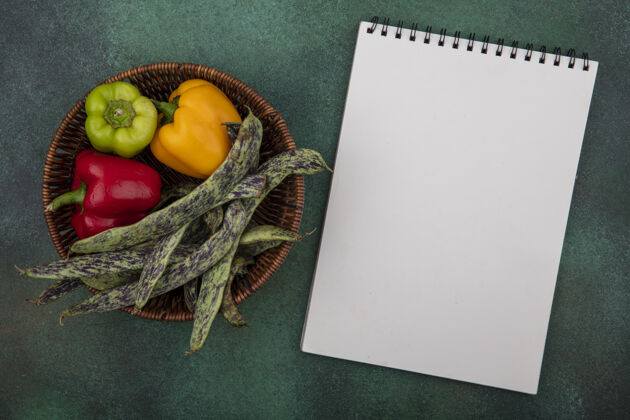 记事本顶视图复制空间白色记事本与绿豆和甜椒在一个绿色的背景篮子铃铛复制胡椒
