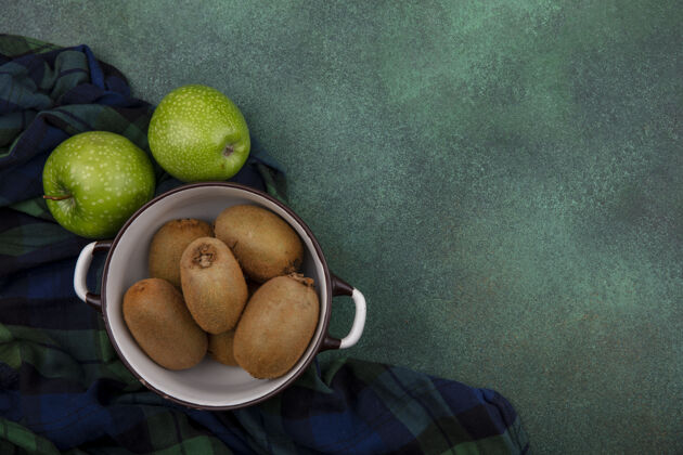 复制顶视图复制空间猕猴桃与绿色背景上的格子毛巾上的绿色苹果锅平底锅苹果格子