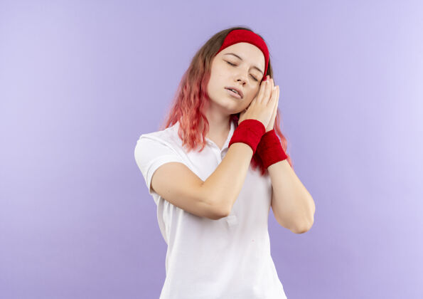 手掌年轻的运动型女人双手合十 头靠在手心上 看起来很累 站在紫色的墙上想睡觉人抱着睡眠
