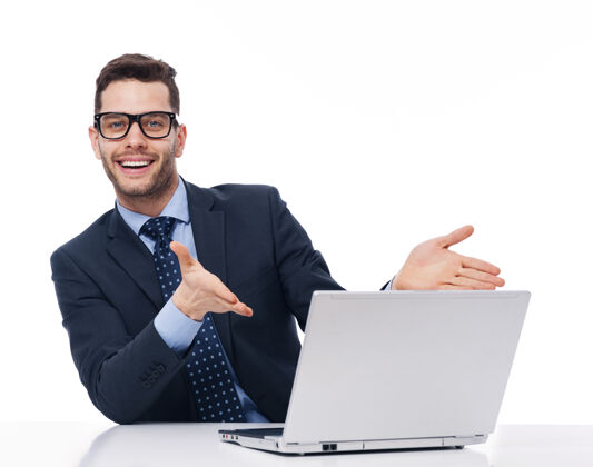 眼镜年轻的商人指着电脑表演成人坐着
