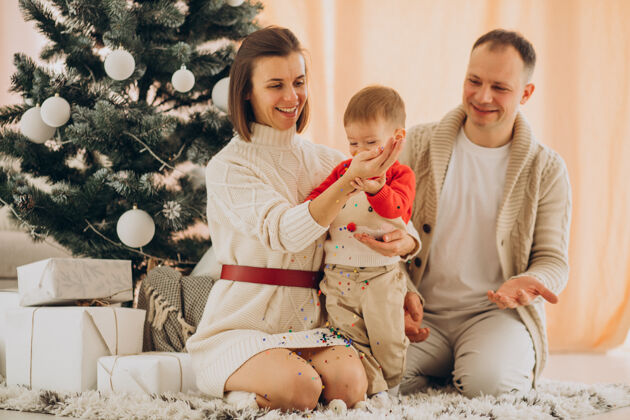 装饰一家人带着小儿子在家里的圣诞树旁现代室内圣诞礼物
