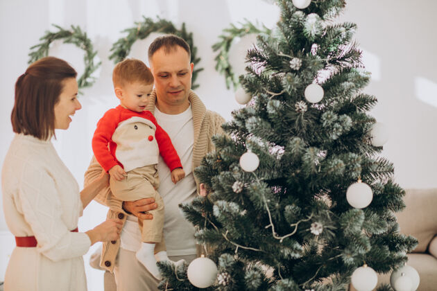可爱一家人带着小儿子在家里的圣诞树旁过圣诞节圣诞圣诞帽装饰