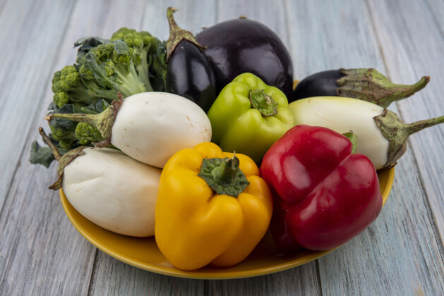盘子侧视图蔬菜辣椒花椰菜和茄子在板上的木制背景食物木头茄子