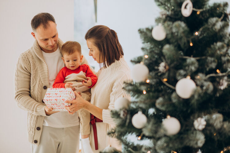 室内一家人带着小儿子在家里的圣诞树旁过圣诞节圣诞庆祝儿子