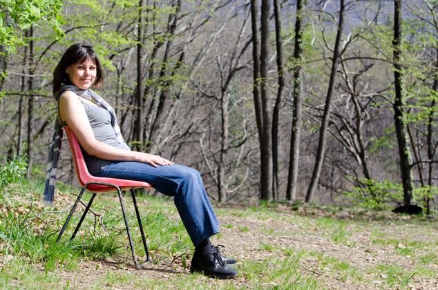 美丽孤独的女人坐在椅子上 在公园里放松思想森林户外