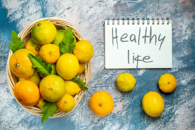 观点顶看柳条篮上的新鲜柑桔健活写在蓝白色的记事本上写作维生素柠檬