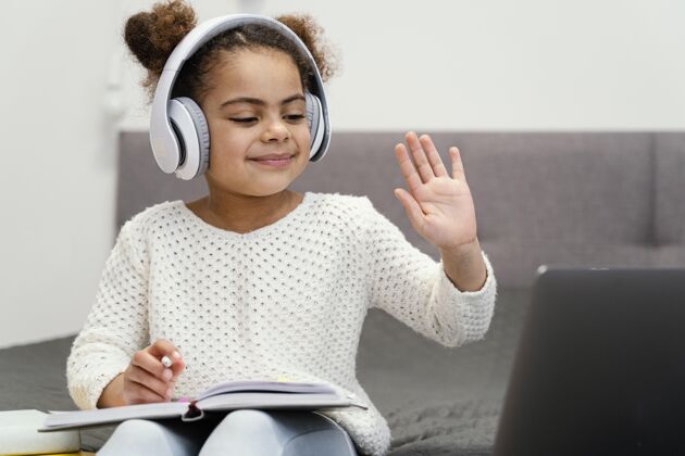 学习小女孩挥手和使用在线学校笔记本电脑的正面图教育课程小
