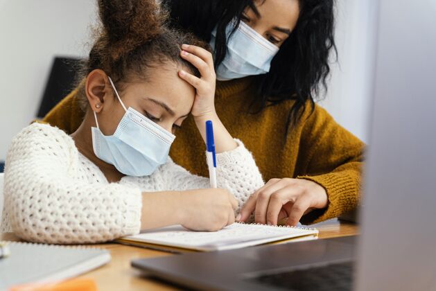 学习小女孩在家戴着医用口罩和大姐上网上学笔记本电脑面罩网络