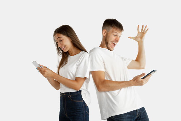 赢家美丽的年轻夫妇的肖像隔离在白色工作室背景上面部表情 人类情感 广告理念男人和女人拿着智能手机 看起来疯狂快乐 庆祝男性情侣惊奇