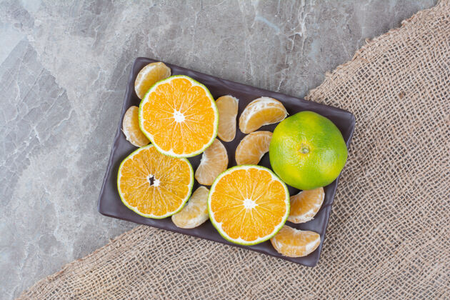 水果一堆橘子和一段一段的放在黑盘子里柑橘切片柑橘