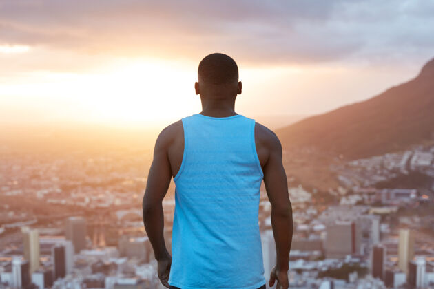 人体格健壮的运动型黑人男性 站在后面 一边思考 一边欣赏自然风光 一边欣赏山城 一边看日出 运动员享受自由运动员肌肉个人