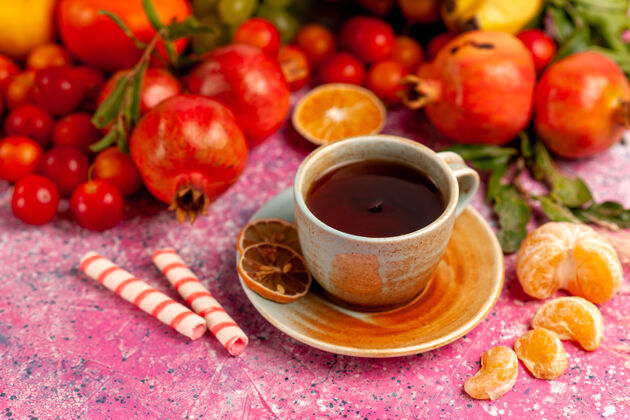 甜前视图新鲜水果组成 浅粉色表面上有一杯茶杯饮食健康