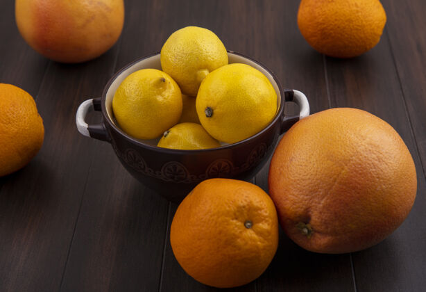 橘子前视图葡萄柚与橙子和柠檬在平底锅上的木制背景平底锅食品木材