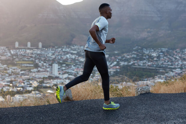 男性阳刚的运动员身材苗条健康的人 穿着运动服 摆姿势 高速奔跑 参加马拉松 对着美丽的城市景色 山景拍照日光教练快速