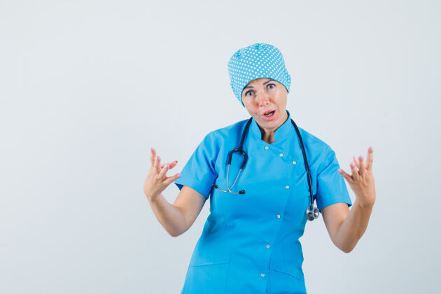 制服身着蓝色制服的女医生举手攻击性地站在正前方诊断肖像成年人