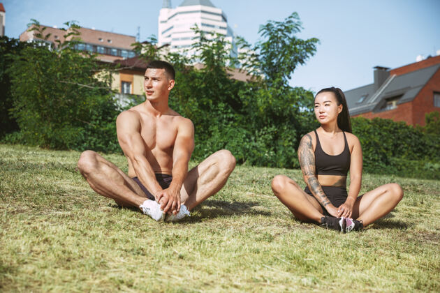 肌肉一个肌肉发达的运动员在公园里锻炼身体体操 训练 健身 柔韧性锻炼夏日城市里阳光明媚的日子背景场积极健康的生活方式 青春 瑜伽 健美英俊活动运动
