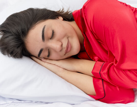 睡衣穿着红色睡衣在床上放松的年轻美女休息和平美丽