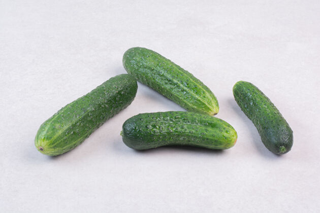 有光泽白色表面上有四个新鲜黄瓜蔬菜有机绿色