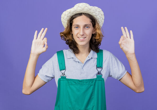 标志年轻的园丁穿着连体衣 戴着帽子 微笑着表示同意帽子站着连身衣