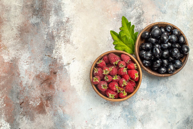 蓝莓顶视图树莓和葡萄在碗叶灰色孤立的表面与复制空间碗顶部覆盆子和葡萄