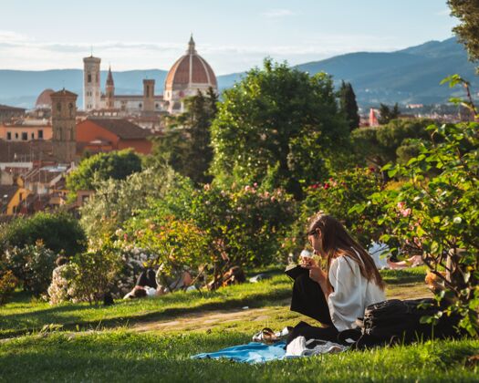 成人只坐在草地上欣赏佛罗伦萨美景的女孩坐着意大利文化年轻人