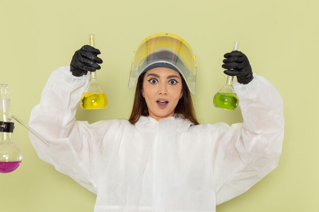 科学正面图穿着特殊防护服的女化学家拿着不同的溶液在绿色表面解决方案护士不同