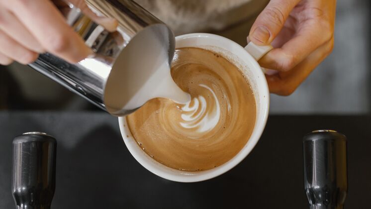 职业男咖啡师在咖啡杯里倒牛奶的俯视图职业雇员服务员