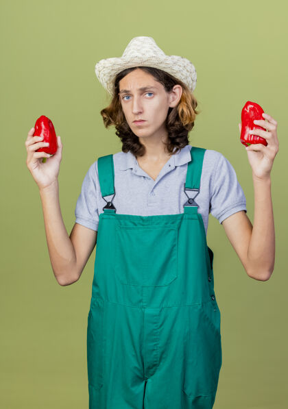 连身衣年轻的园丁 穿着连体衣 戴着帽子 手里拿着红甜椒年轻帽子脸