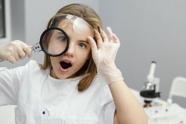 青年年轻女科学家用放大镜的前视图化学学习女孩
