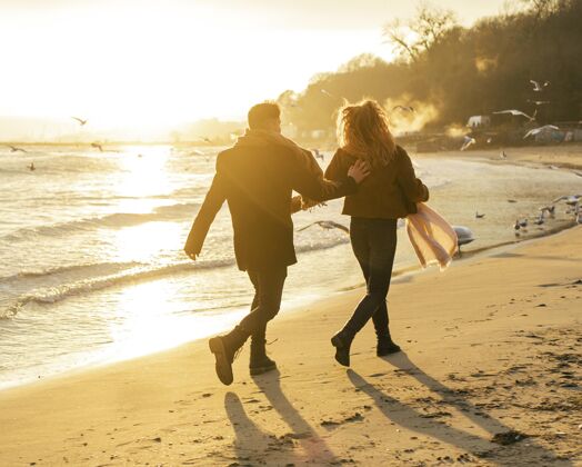 女人冬天情侣在沙滩上散步的背影冬天水平休闲