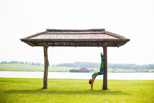 饮食年轻漂亮的女人在湖边的晨间公园做瑜伽专注树自然