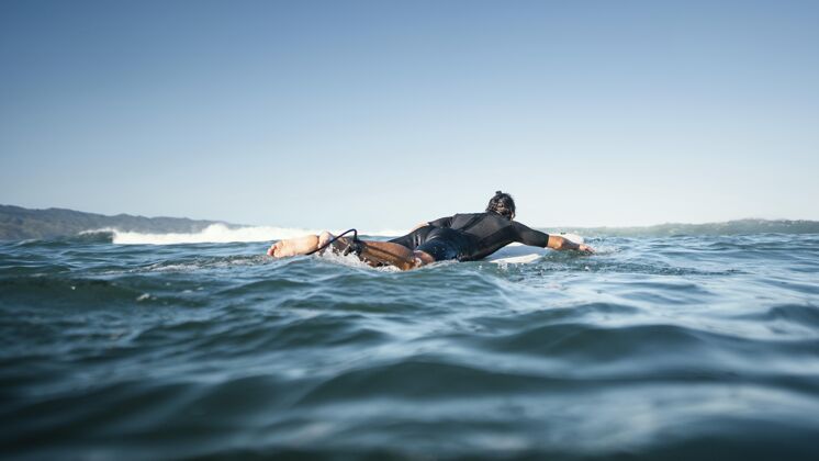 运动员冲浪板上的人游得很远生活方式海洋日光
