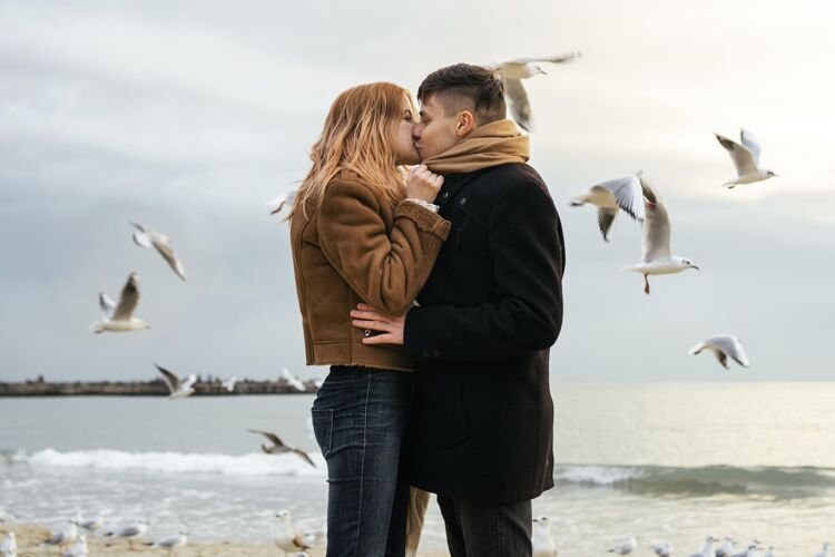 消遣海边的年轻夫妇在冬天的侧视图女人季节情侣