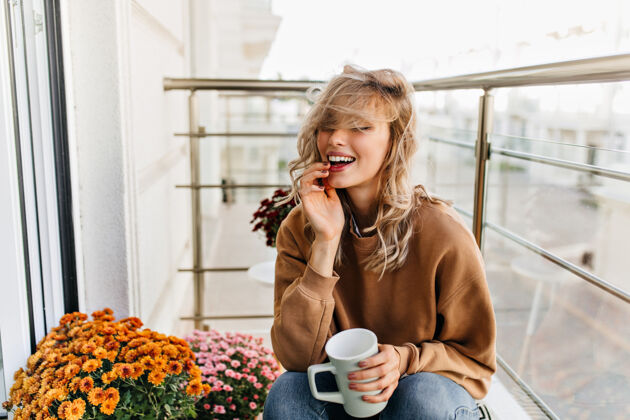 金发女子快乐的白人女孩在阳台上喝茶美丽的年轻女子在阳台上凉快模特年轻女子意式浓缩咖啡