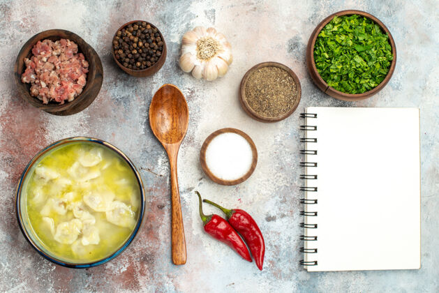 笔记本俯瞰杜什巴拉碗不同香料绿色肉木勺笔记本上裸体表面食物照片绿色肉视图