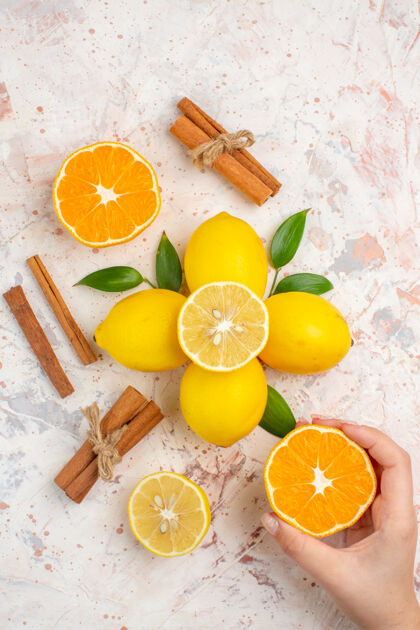 柠檬顶视图新鲜柠檬切橘子肉桂棒切橘子在女性手上明亮孤立的表面柑橘棒维生素