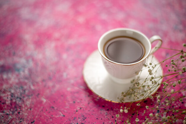 里面正面是粉红色桌子上盘子里的一杯茶杯子茶碟咖啡