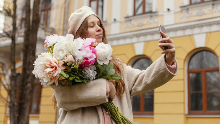 春天春天里 一个时髦的女人拿着花束在户外自拍春天花智能手机