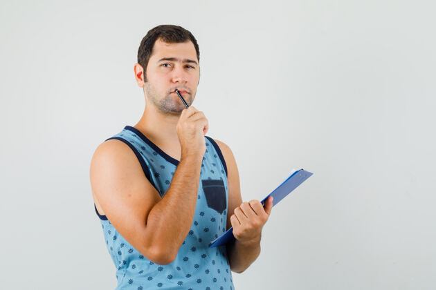 男穿着蓝色单品的年轻人手里拿着写字板和笔 神情沉思成功自信胡须