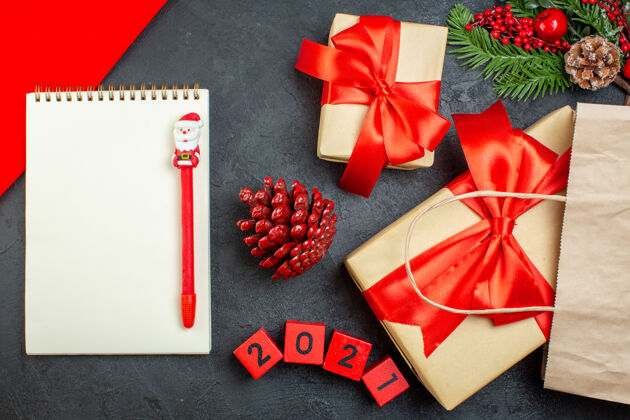 钢笔xsmas心情笔记本俯视图 黑色桌子上有钢笔针叶树球果和礼品冷杉树枝数字包装冷杉圣诞节