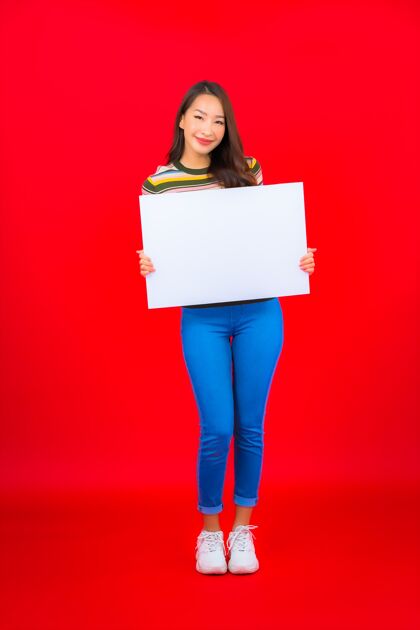 中文在红墙上用白色的空广告牌描绘美丽的亚洲年轻女子模特休闲商务