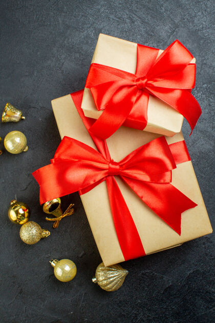 轮子黑色背景上带有红丝带和装饰配件的礼品盒的垂直视图蝴蝶结圣诞节礼盒