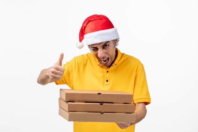 工人正面图白色墙壁上有披萨盒的男快递员新年工作服披萨男信使服务