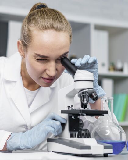 专家女研究员在实验室用显微镜的正视图技术员试管创新者