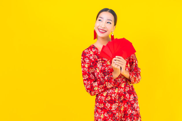 红包在黄色的墙上画一幅美丽的亚洲年轻女子拿着红包服饰金融历史