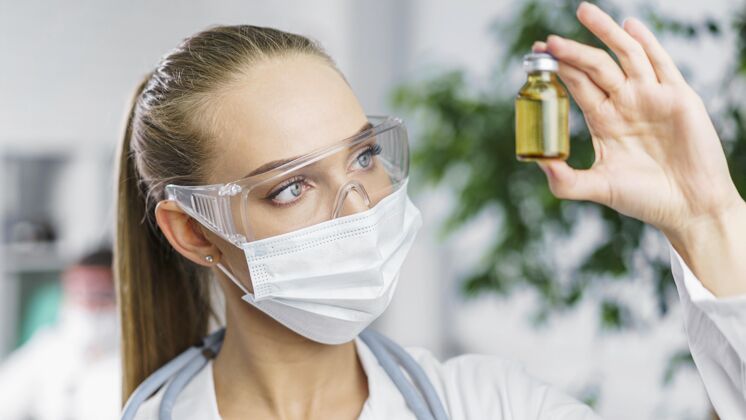 技术员戴着医用面罩和疫苗的女研究员的正面图瓶子专家创新