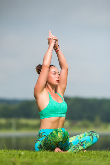 美丽美丽的女人在绿色公园做瑜伽练习冥想莲花人