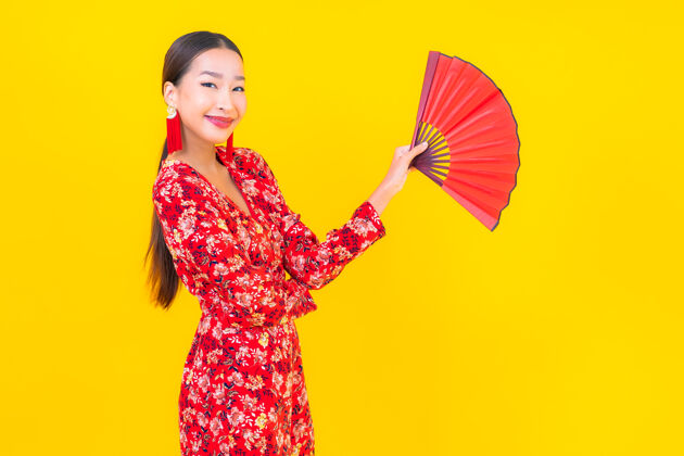 春天美丽的亚洲年轻女子在彩色墙上的中国新年概念中的微笑手历史金融
